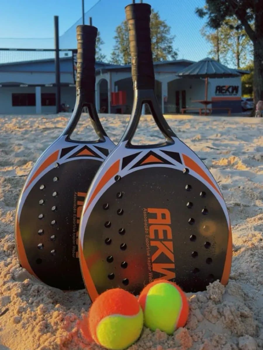 Raquetes e bolas de beach tennis da AEKW na quadra